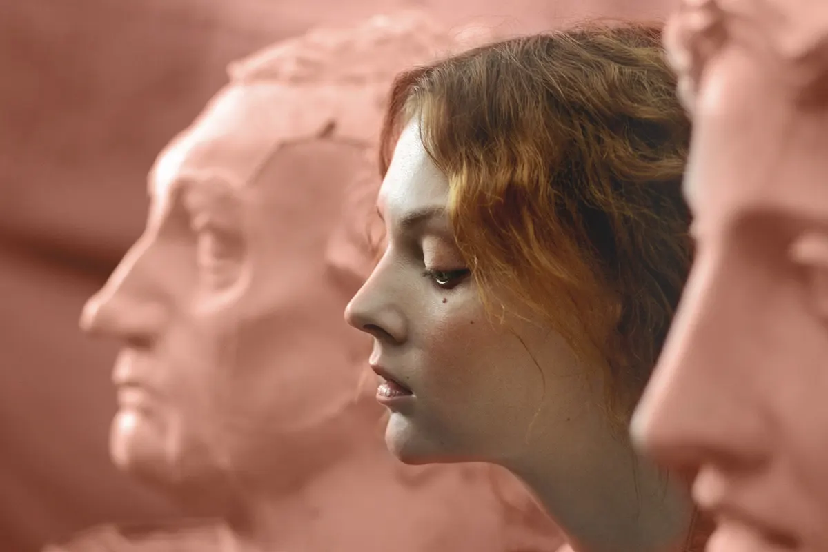 Jóven mujer entre estatuas de mármol imita sus rostros.